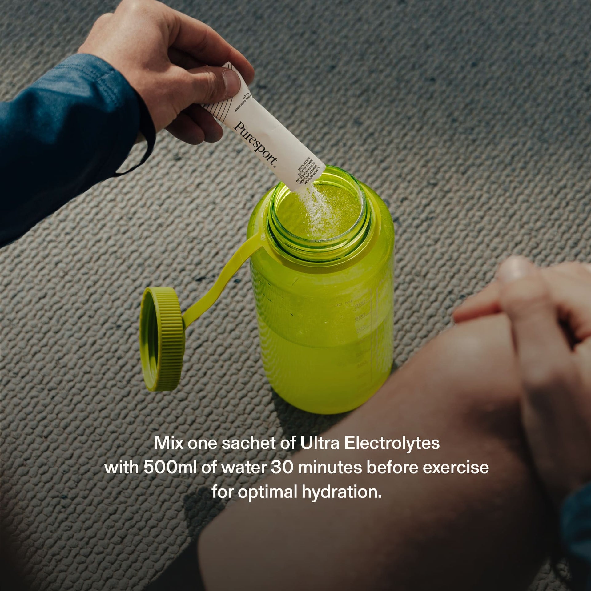 Person adding electrolyte powder by Citrus Salt flavour by Puresport into to a green sports bottle.