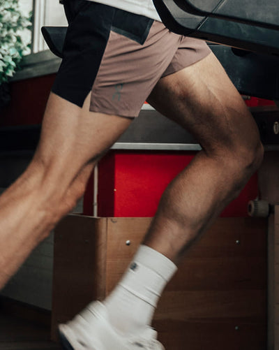 Person wearing brown shorts and white socks running on a treadmill