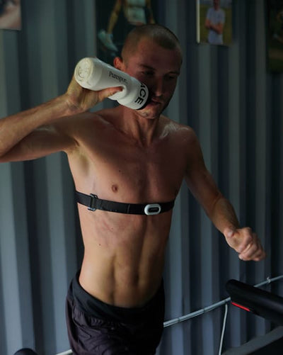 Man exercising on a treadmill with a bottle of water in his hand.