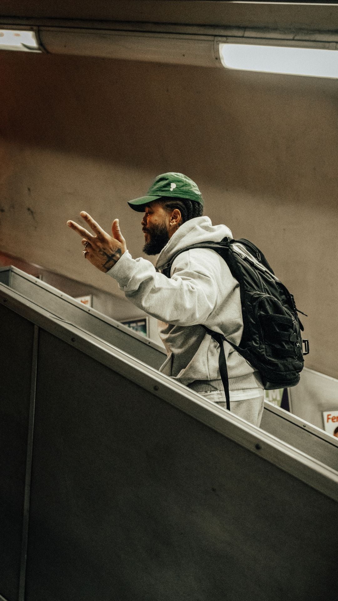 A guy walking up the stairs in a green Puresport cap. 