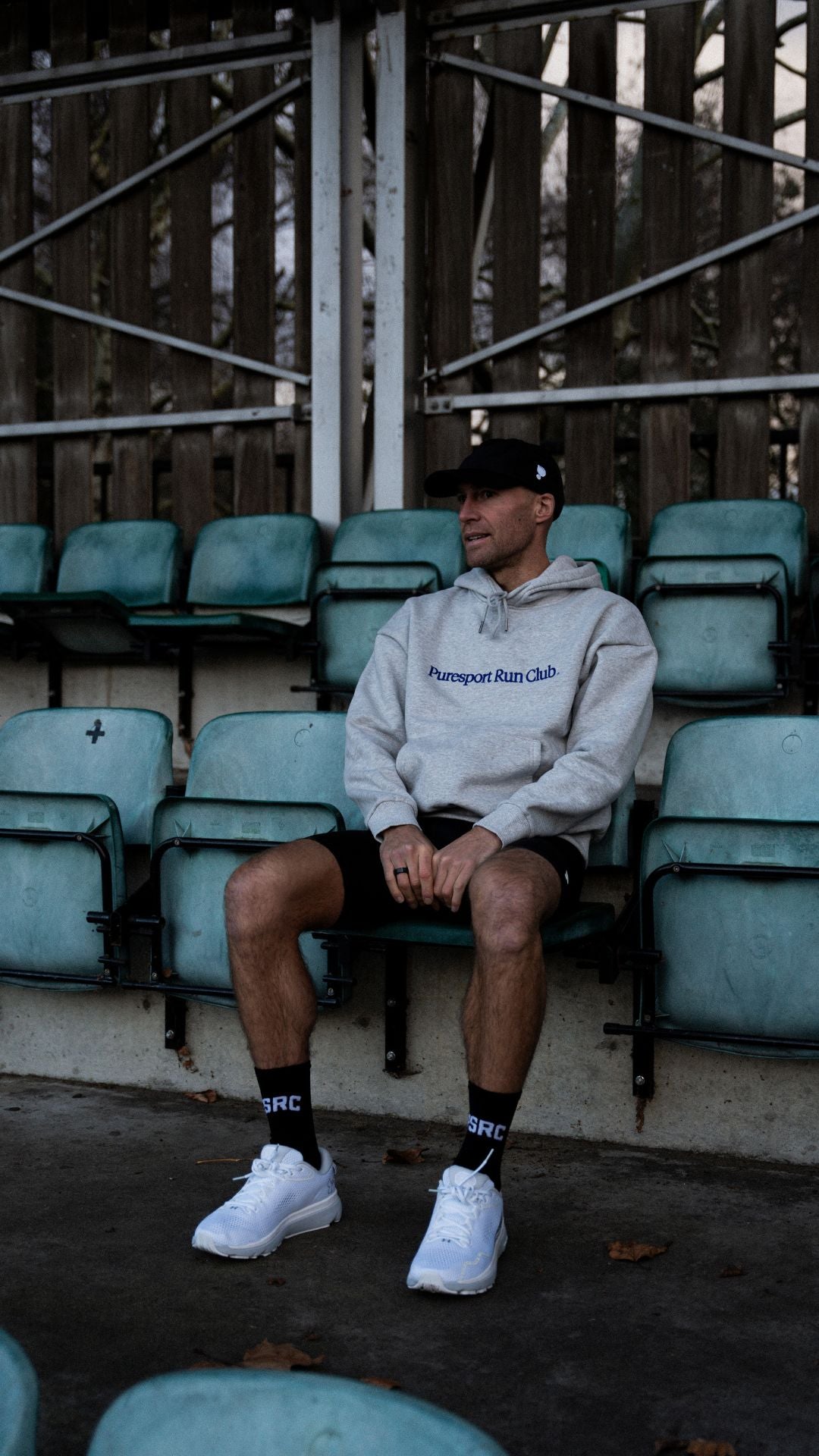 Athlete sitting on a bench in an outdoor track and field wearing a hoodie with Puresport branding.