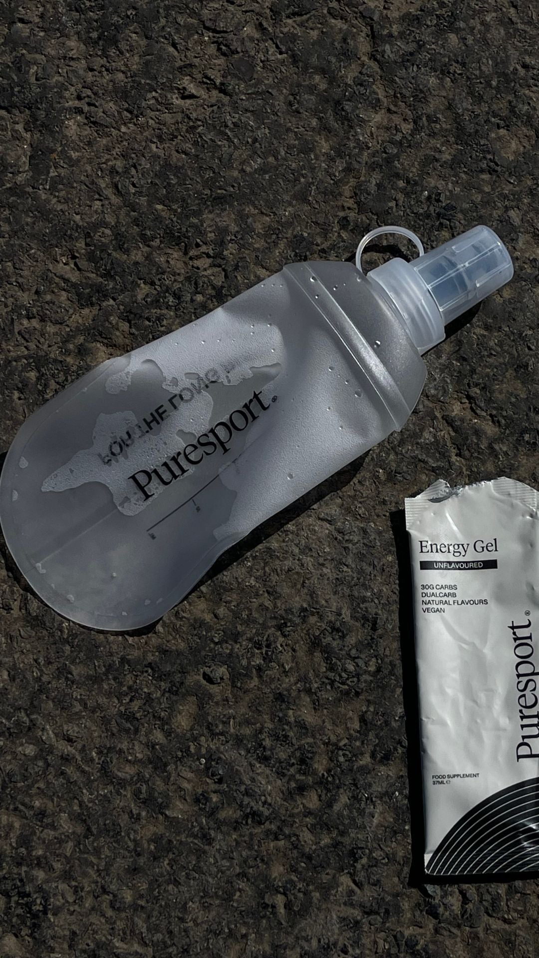 Puresport water bottle and energy gel on a dark surface