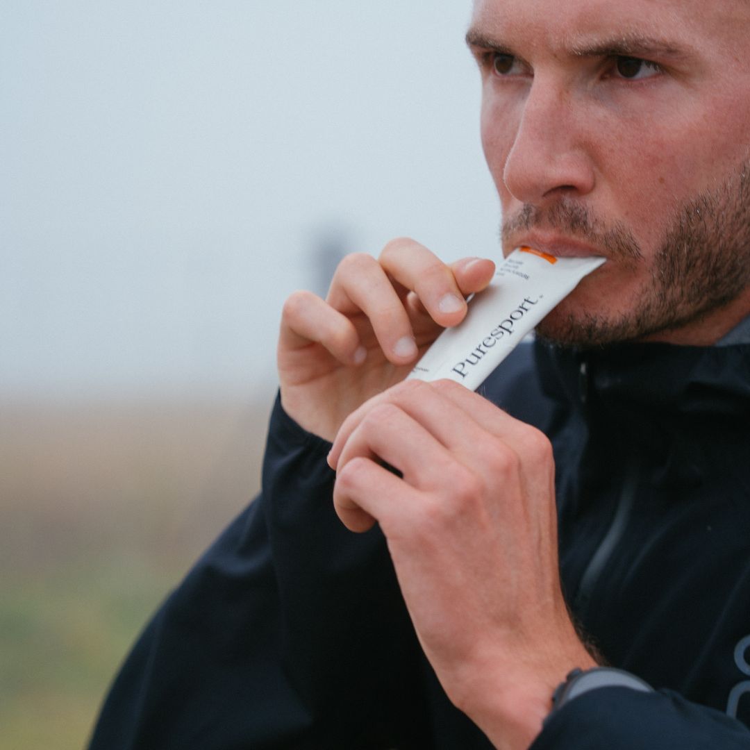 George Mills  holding a PureSport energy gel in the outdoors. 