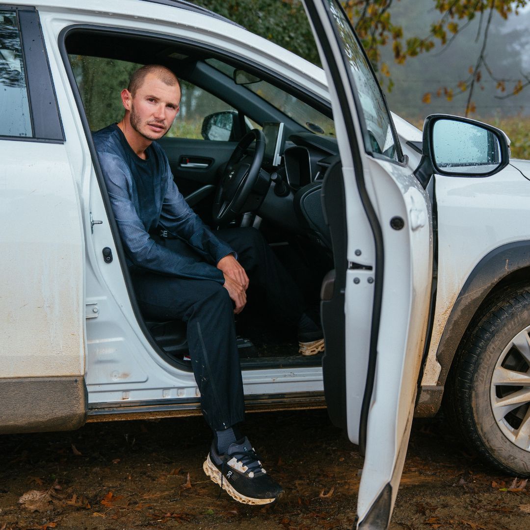 George Mills sitting in a white SUV with the door open, outdoors.