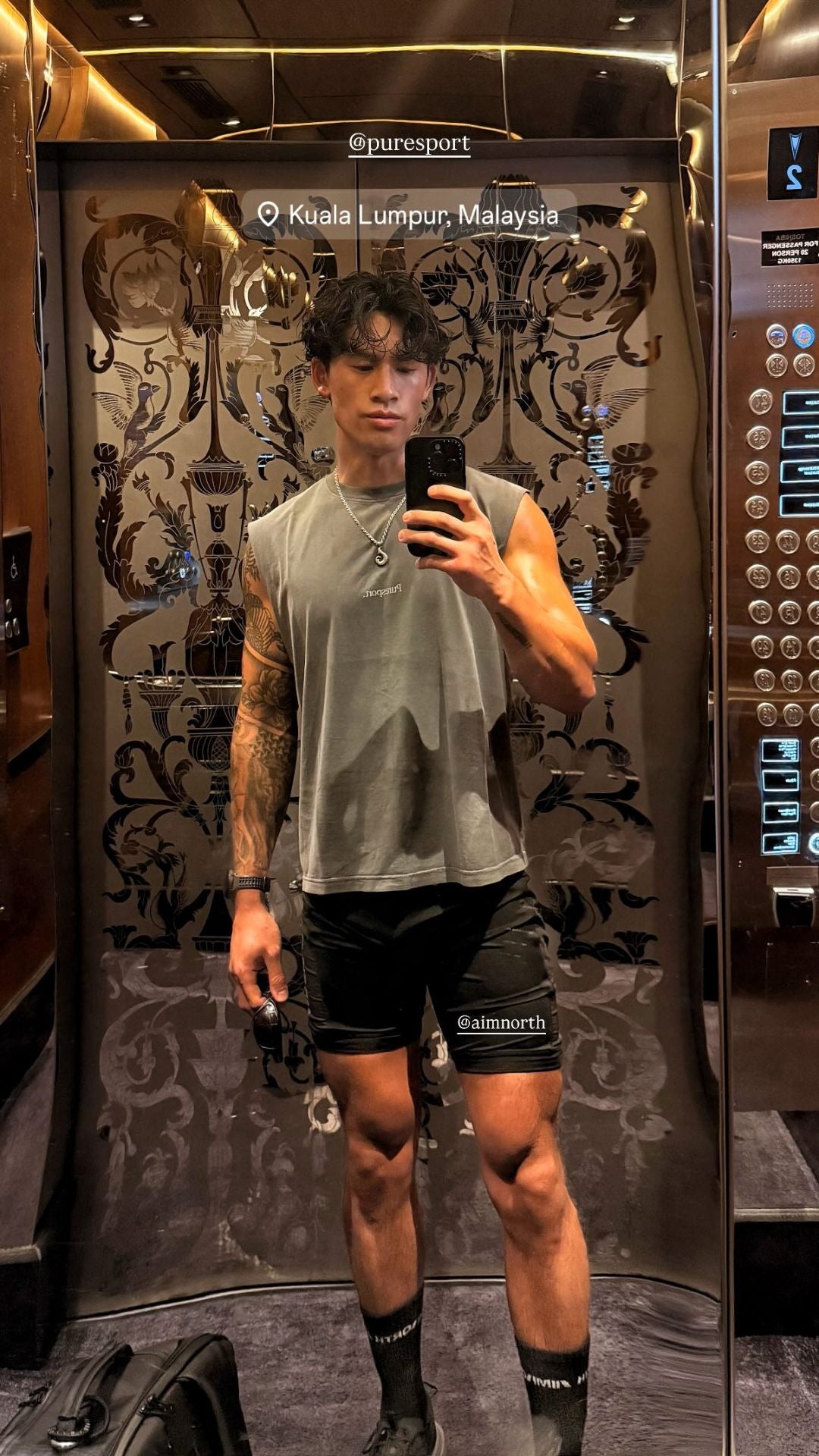 Person taking a mirror selfie in a public restroom with visible branding wearing a Puresport top.