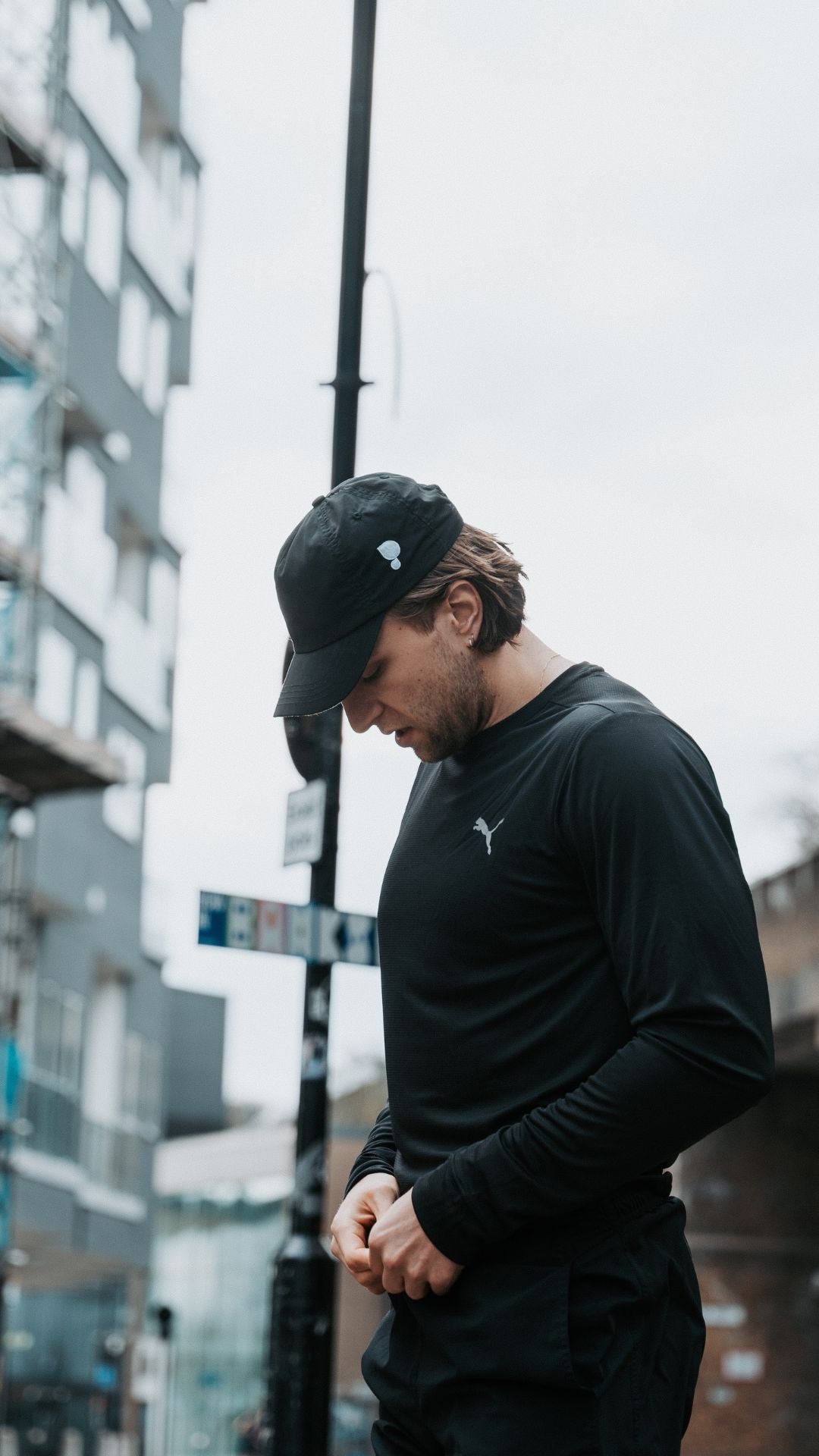 Runner wearing a black cap by Puresport and black Puma shirt on a city street. 