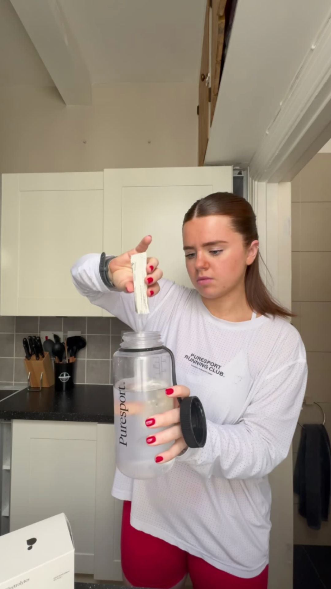 Woman in a kitchen holding a large nalgene bottle with Puresport electrolytes