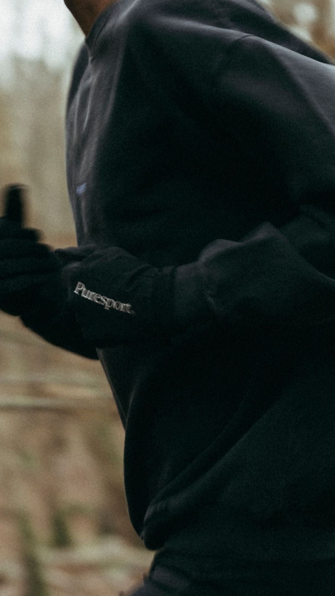 Running wearing a black jacket with 'Puresport' branded run gloves in a forest setting