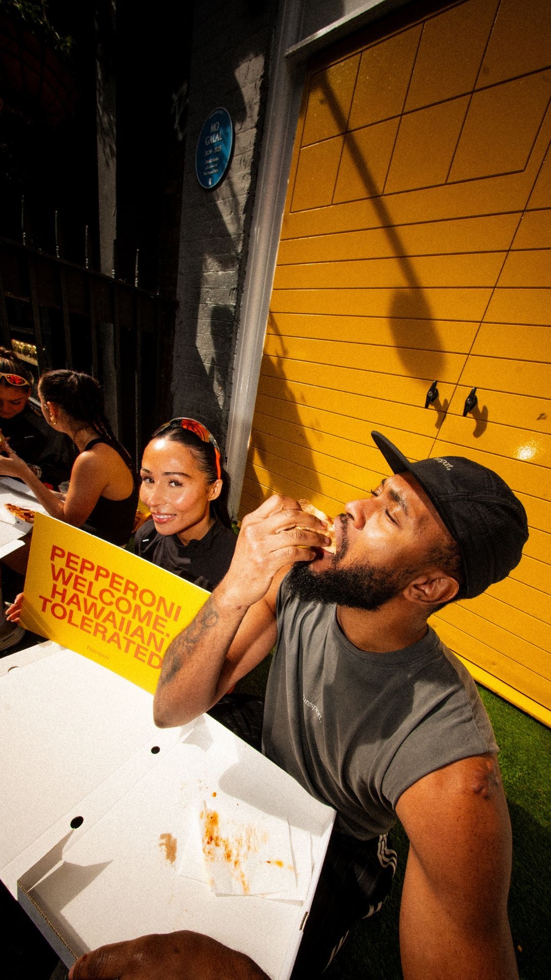 Two people sitting eating Pizza at Puresport x HouseParty in Soho 