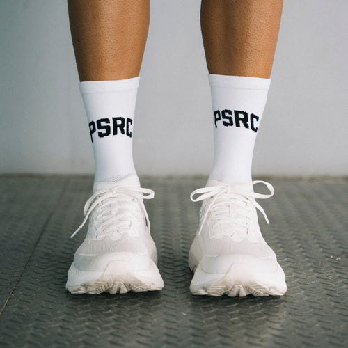 White sneakers and socks with 'PSRC' branding on a textured surface.