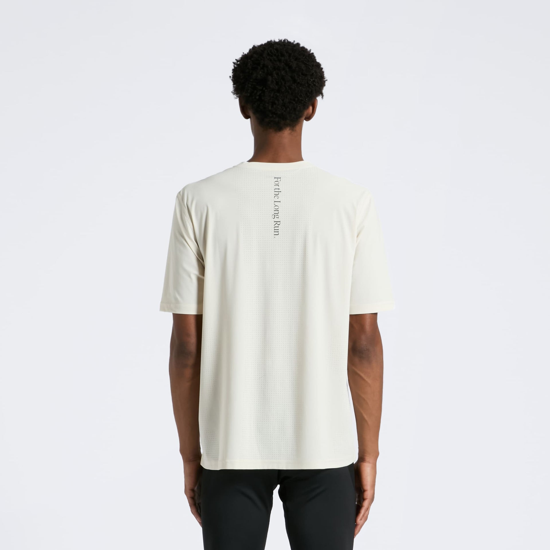 Person wearing a sand t-shirt with For the Long Run on the back against a light grey background