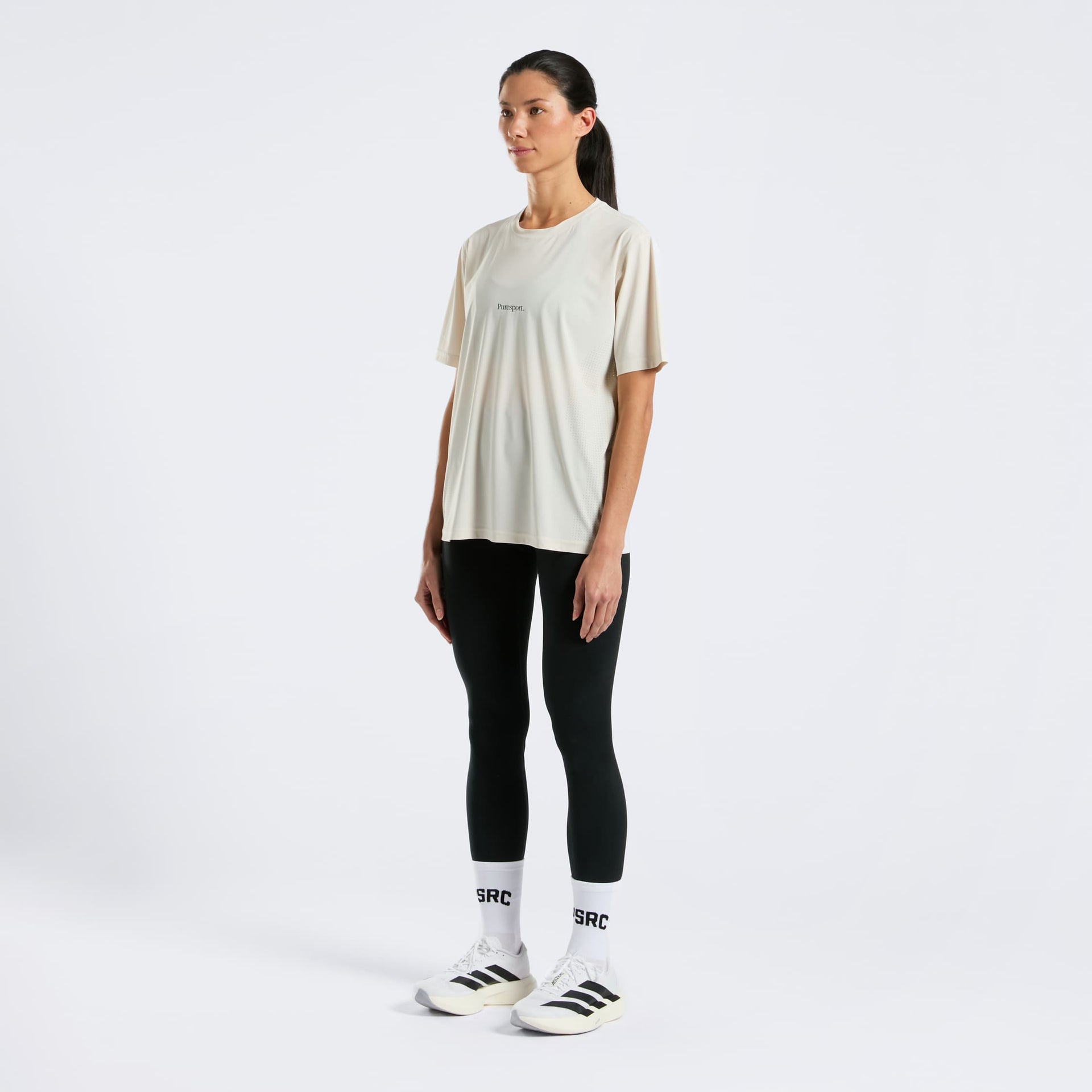 Women runner wearing a sand t-shirt, black leggings, and white sneakers with 'PSRC' branding on a white background