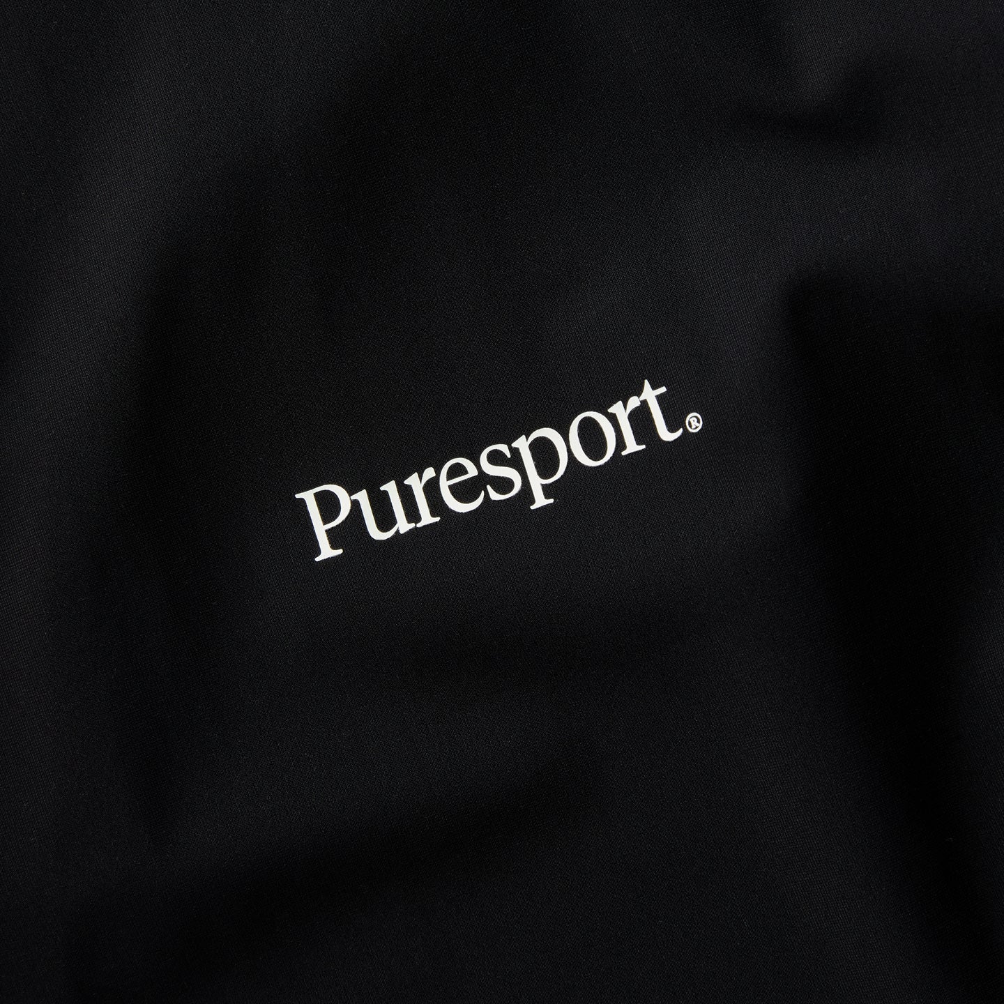 Black fabric with 'Puresport' logo embroidered on it