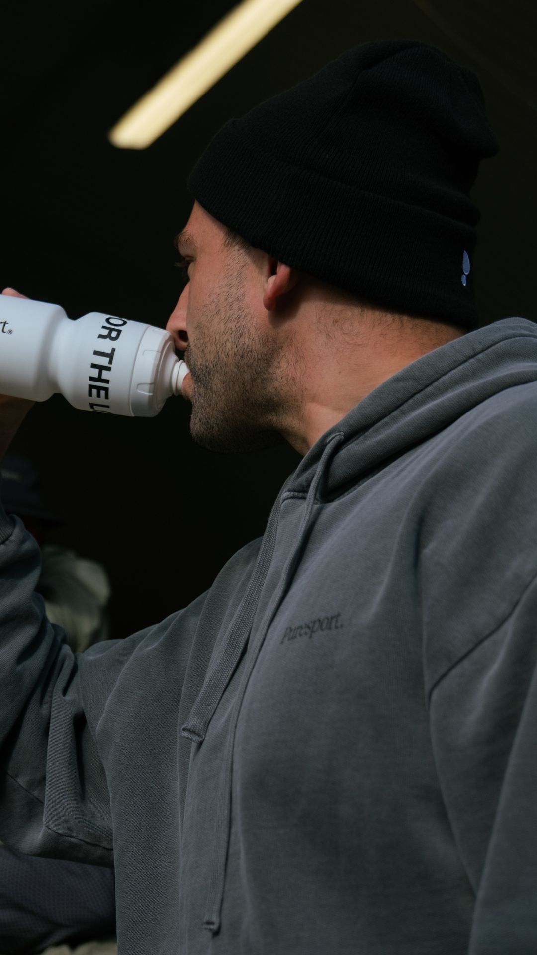 Person drinking from a Puresport water bottle with a dark background
