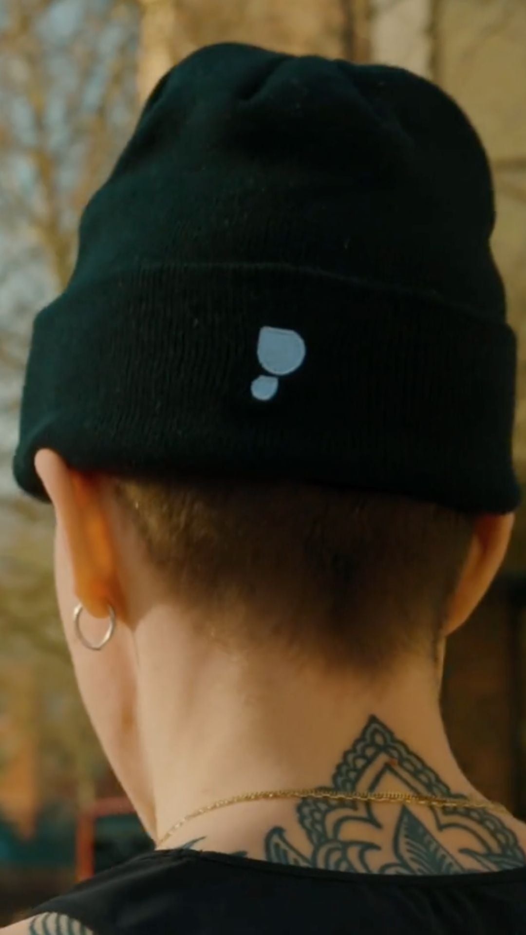 Runner wearing a black beanie with a sweat drip logo, back view