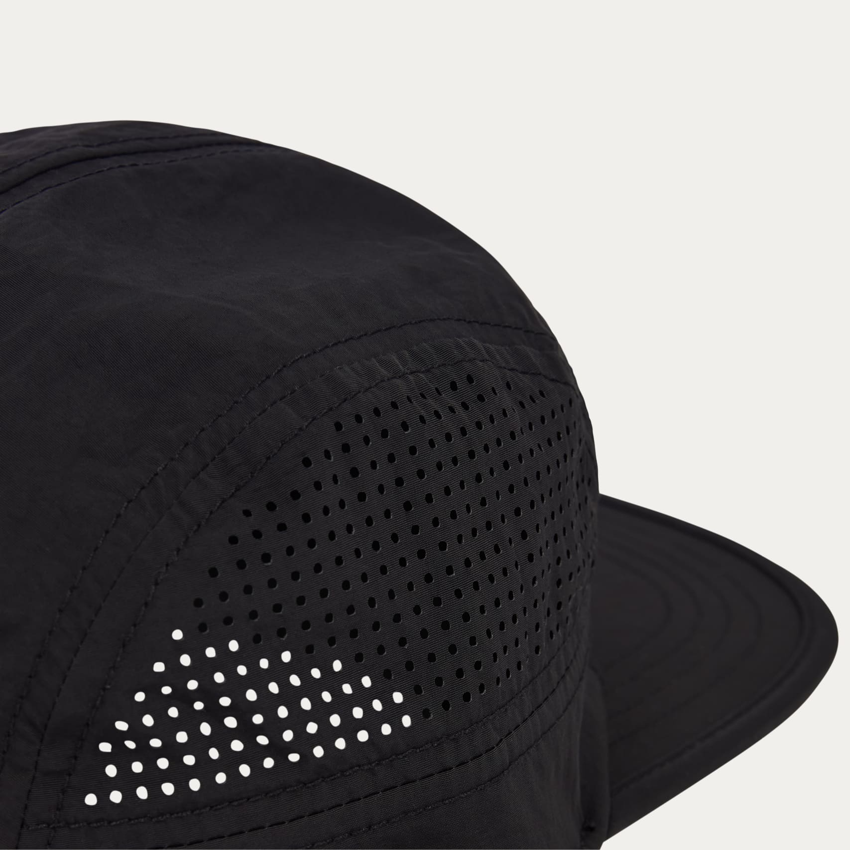Black run hat with a laser cut holes for breathability on a light grey background