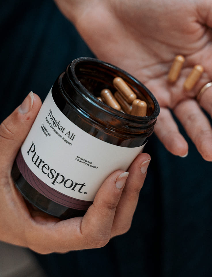 Person holding a jar of Puresport Tongkat Ali capsules.