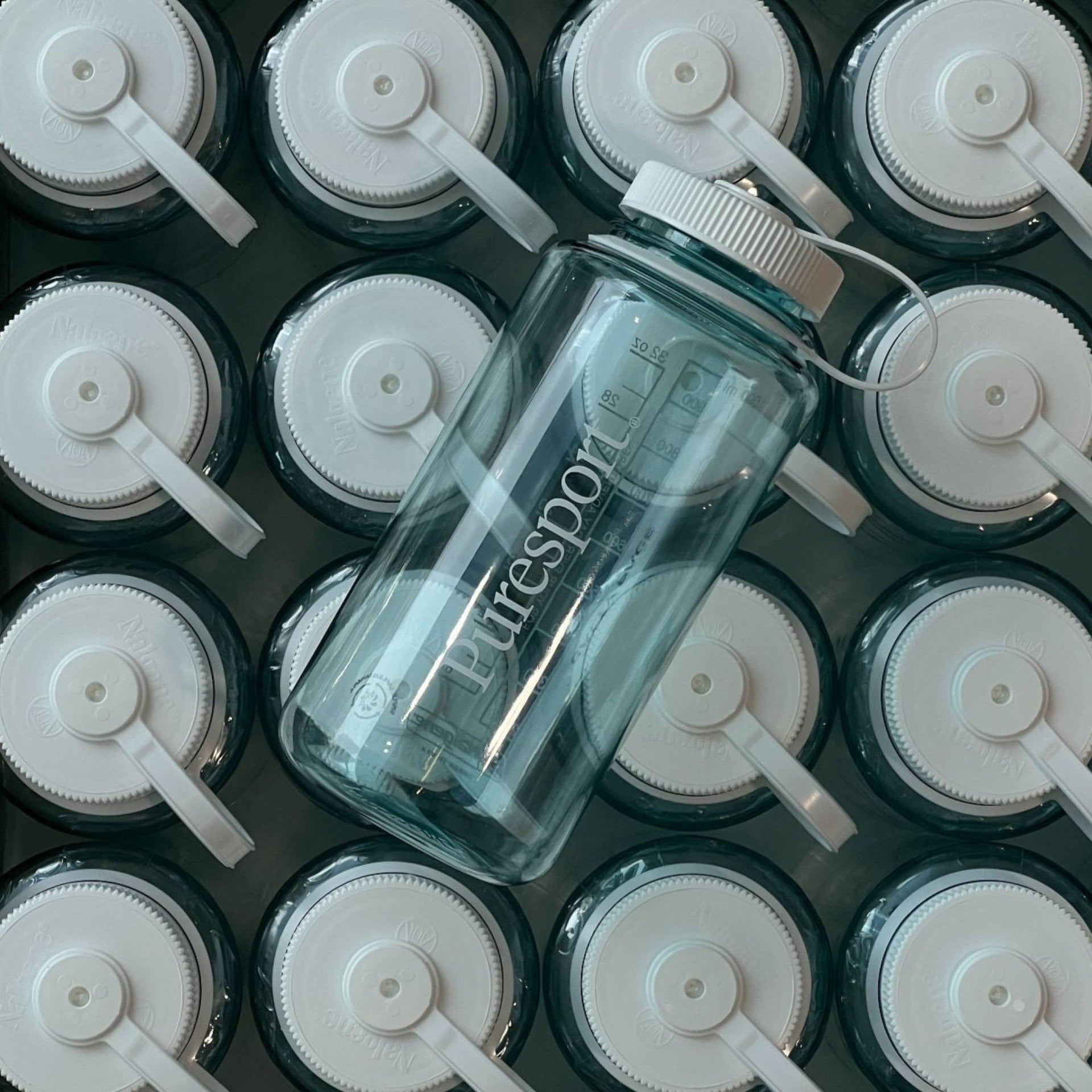 Clear water bottle with white lid on a grid of similar bottles