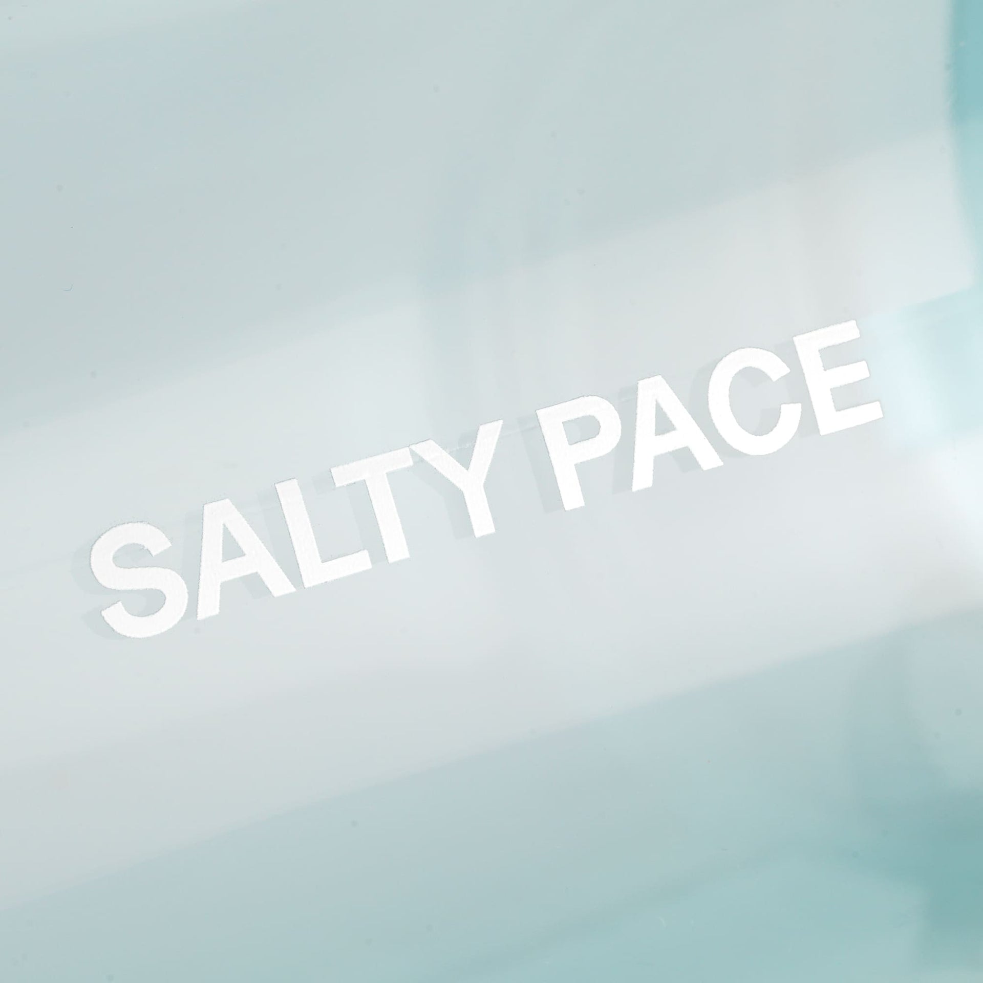 Text 'SALTY PACE' on a seafoam bottle