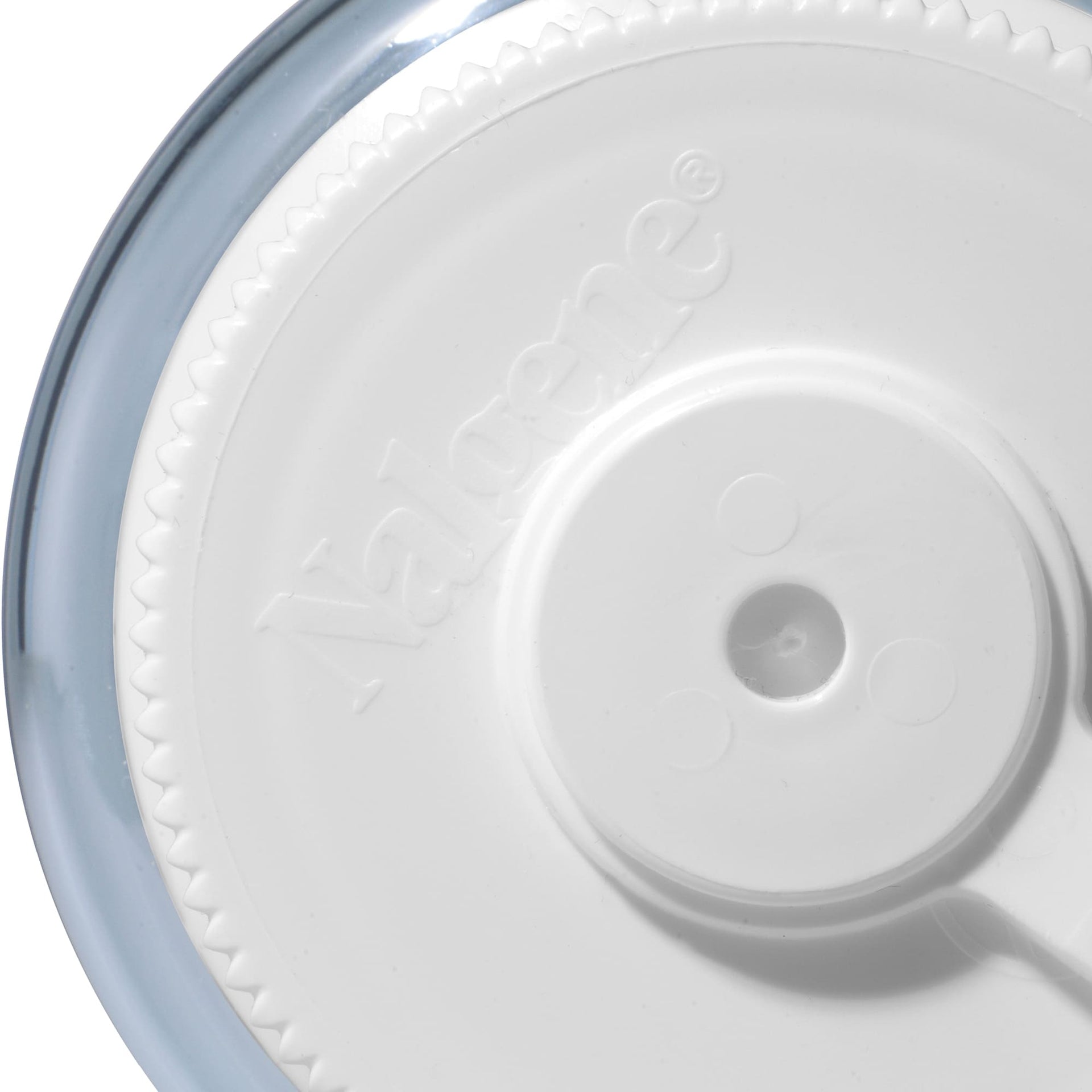 Close-up of a white plastic lid on a bottle with a central hole on a light grey background