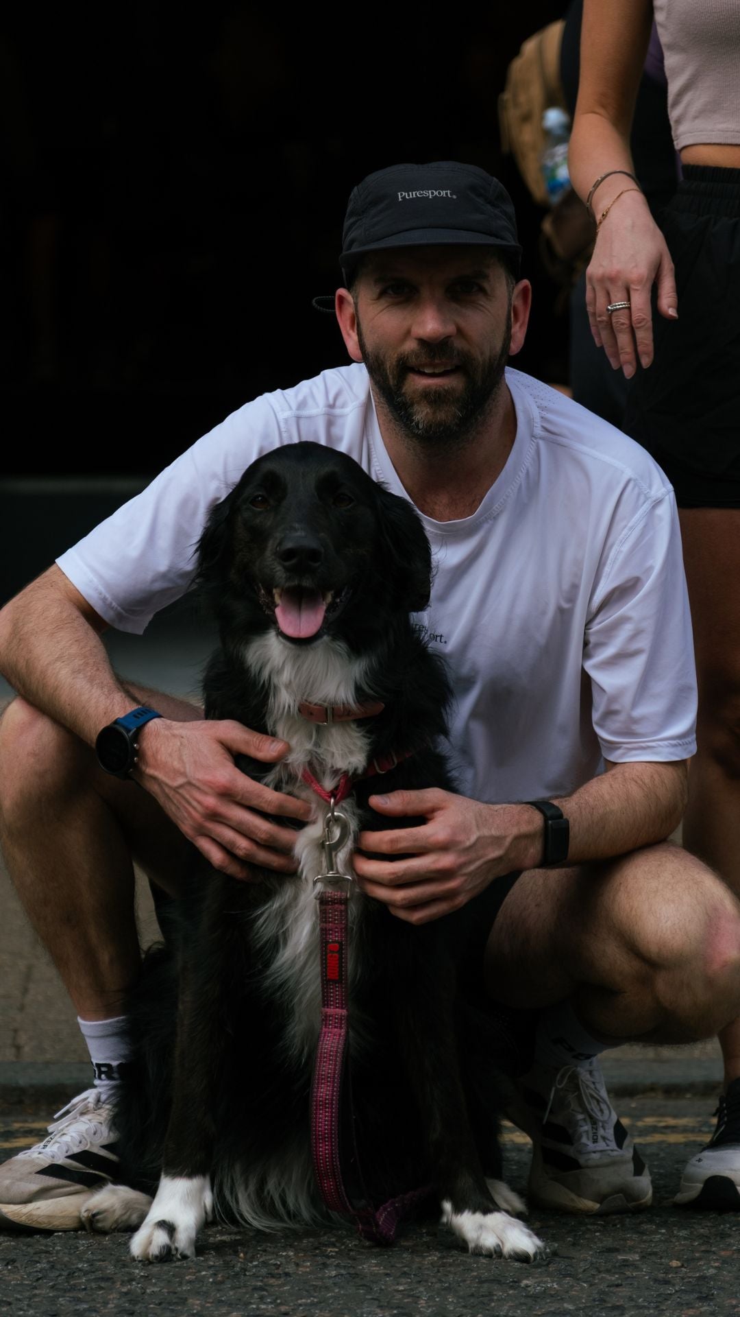 Man with a dog sitting on the ground at  Puresport running club. 