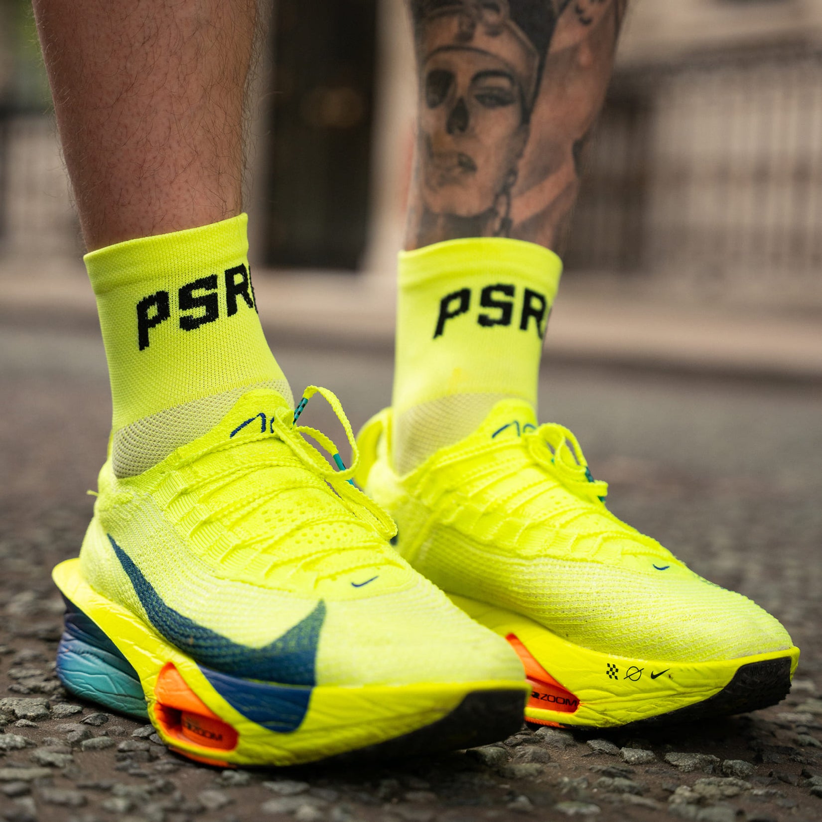 Neon yellow nike run shoes with 'PSRC' socks on a blurred street background