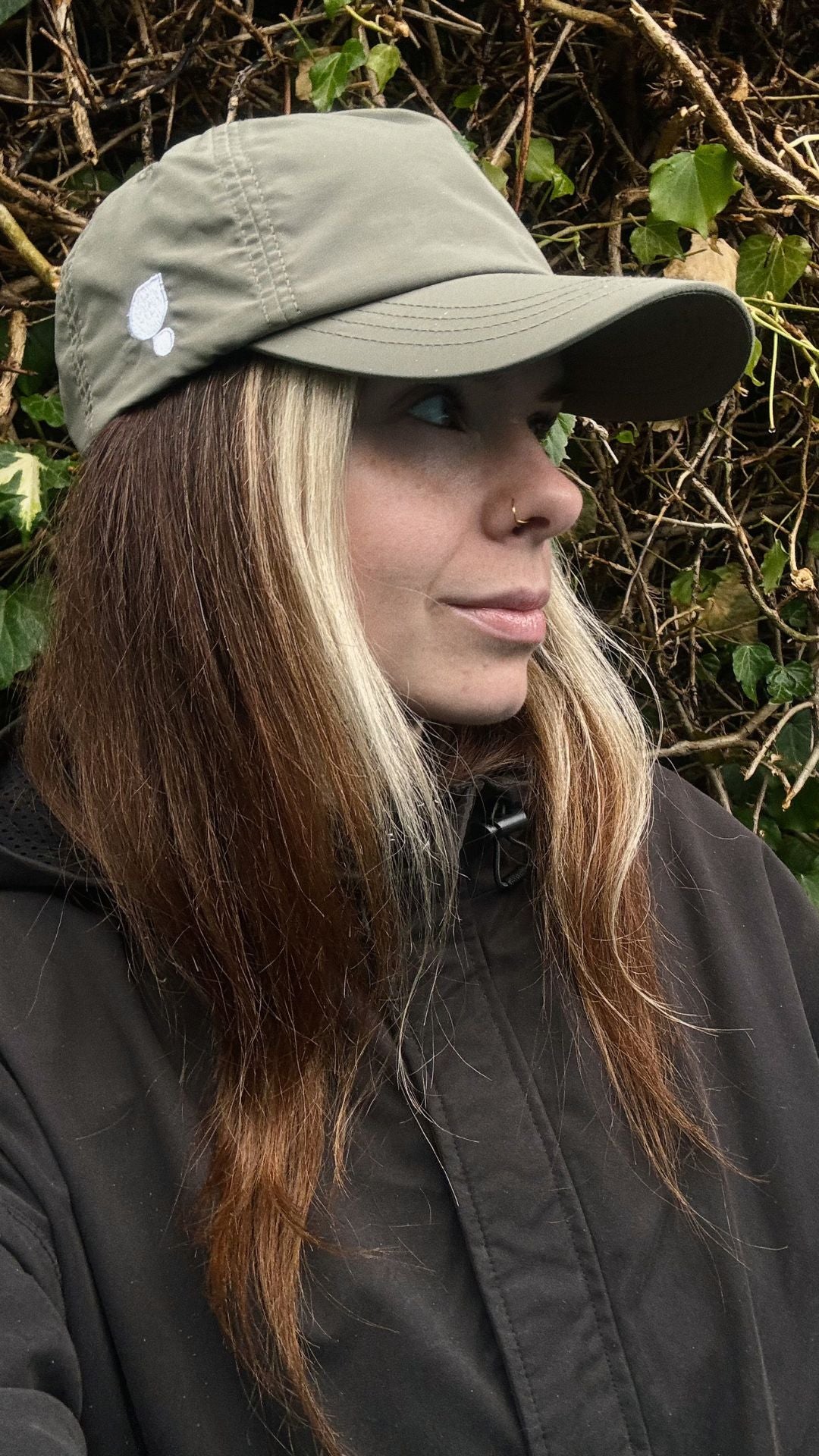 A women runner wearing a sage running cap by Puresport against a natural background