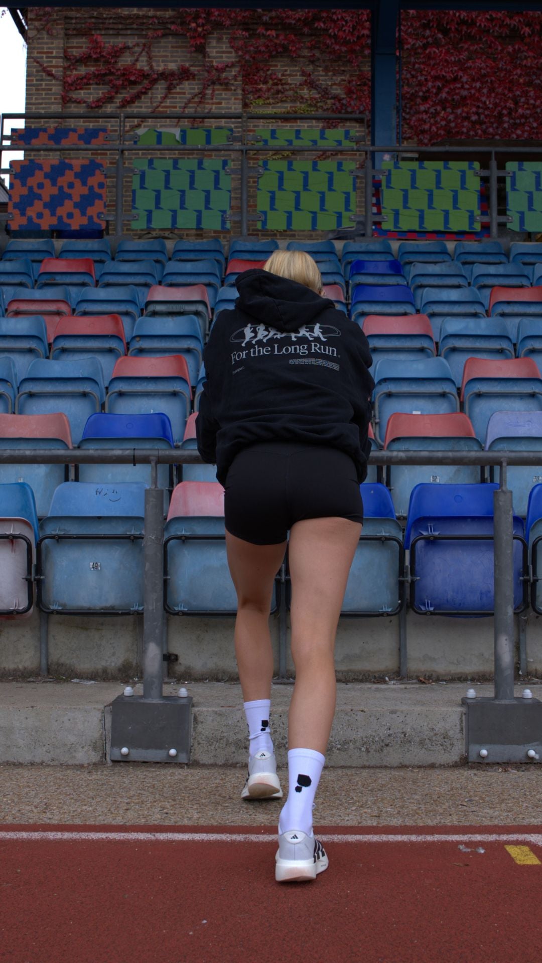 Athlete stretching in a track and field stadium with colourful seats. 