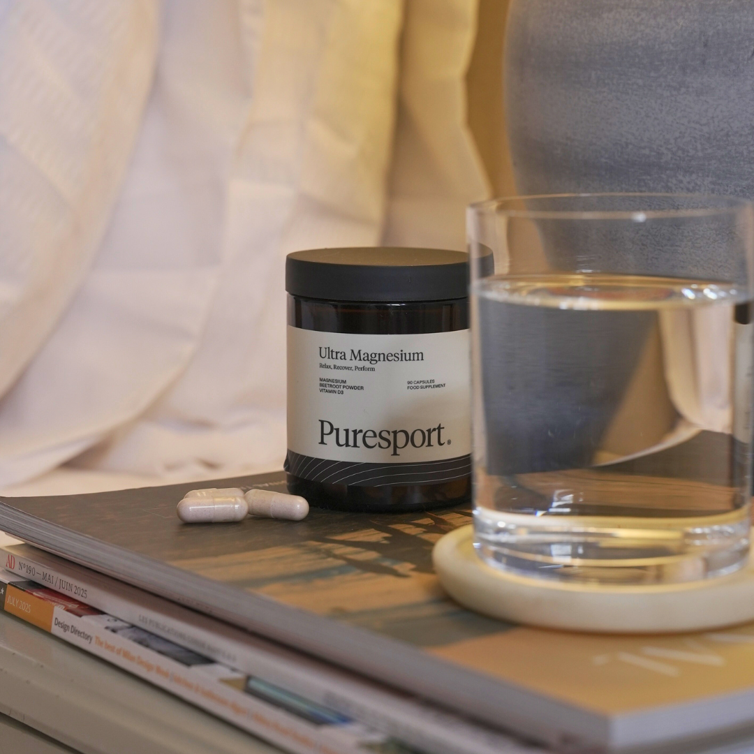 Puresport Ultra Magnesium supplement jar with a glass of water and pills on a night stand table. 