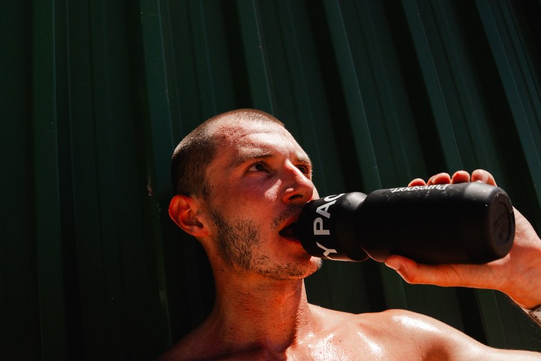 Athlete drinking from a Puresport bottle after training in the sun